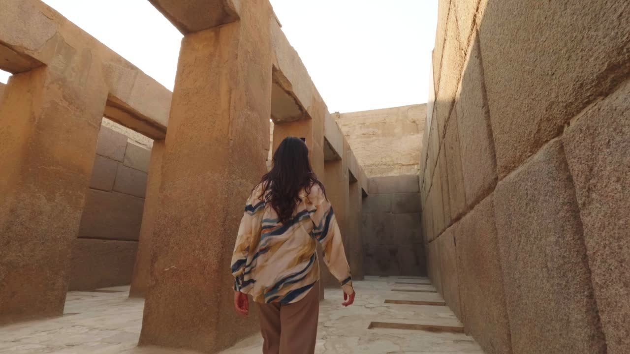 Mulher Caminhando por uma Antiga Estrutura de Templo de Pedra