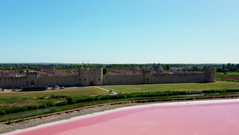 the historical town of aigues-mortes in the camargue, france during a sunny summer day which is located next to a pink salt lake