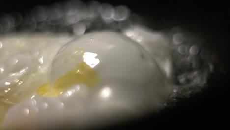egg white bubble close up in a black frying pan with hot boiling oil with soft bokeh