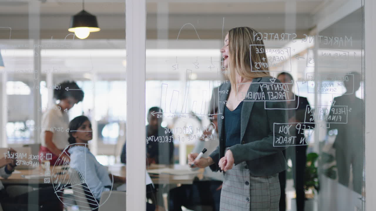 아름다운 비즈니스 여자가 유리 화이트보드에 글을 쓰고 팀 리더가 회의에서 동료들을 훈련시키고 브레인스토밍 문제 해결 전략 사무실에서 아이디어를 공유합니다 프레젠테이션 세미나 4k