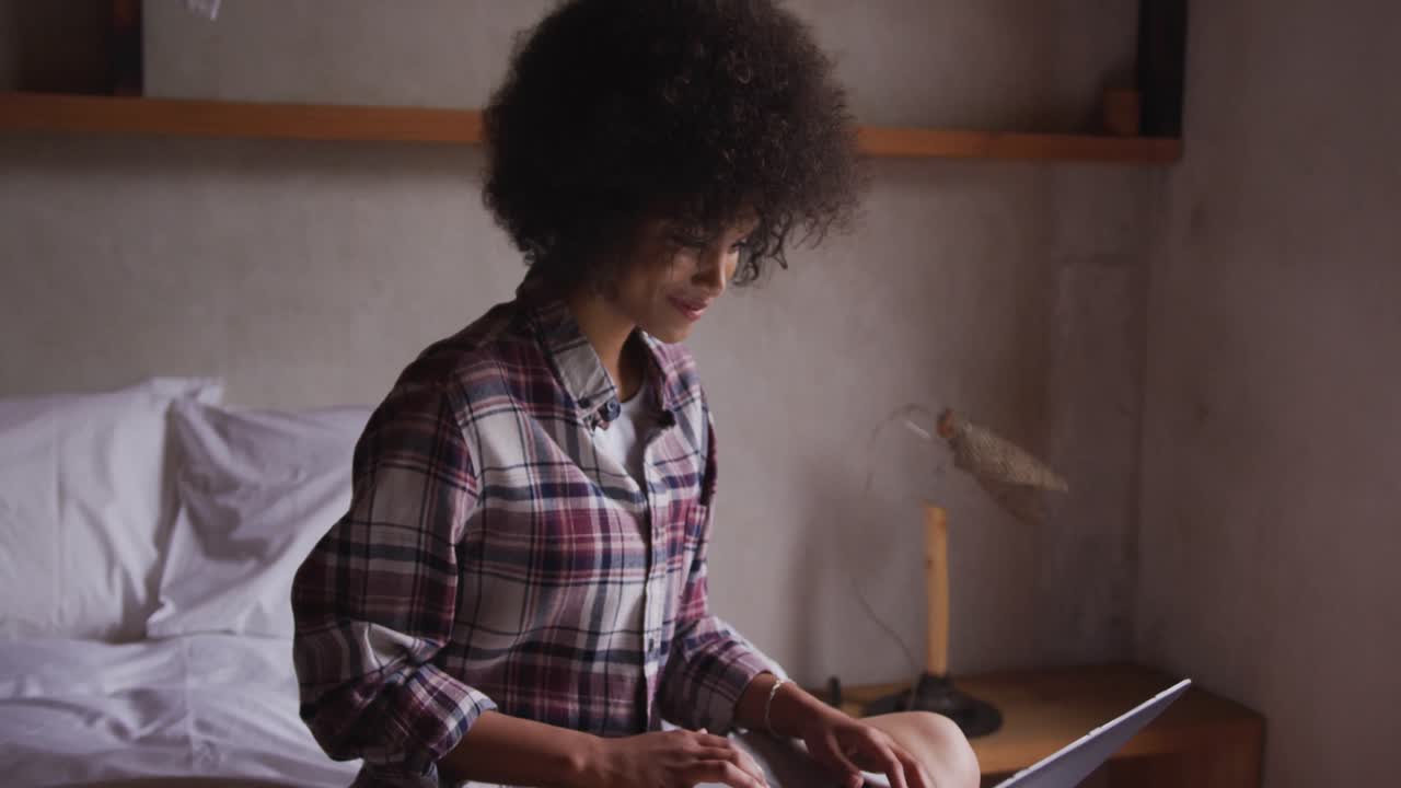 mujer de raza mixta usando computadora en el dormitorio