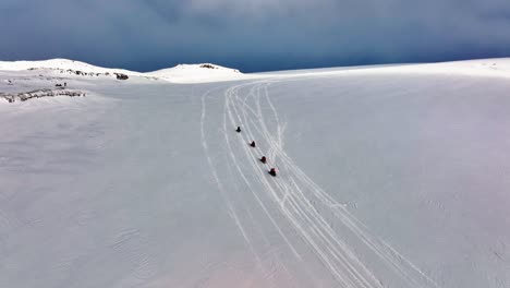 aerial landscape view of people riding snowmobiles on the icy ground of myrdalsjokull glacier in iceland