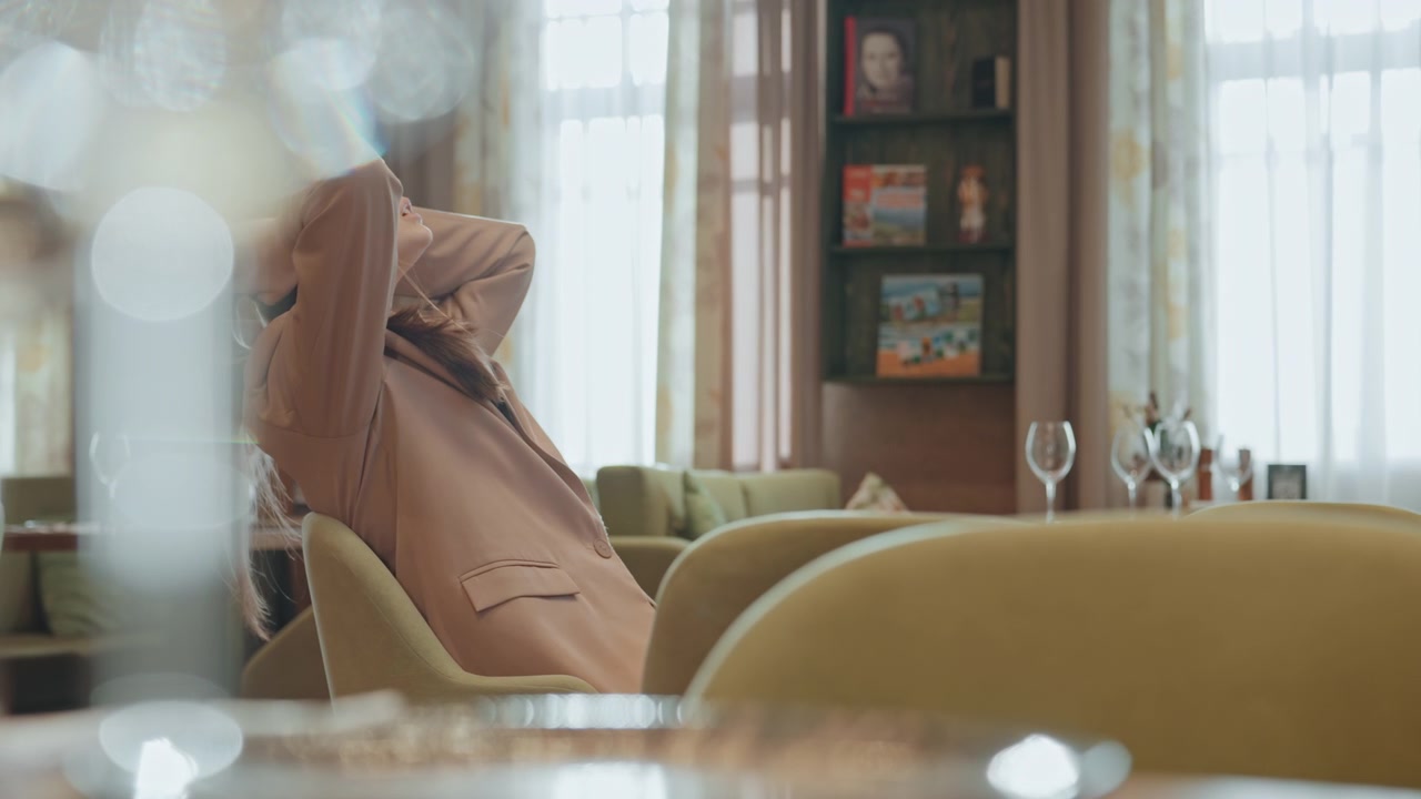White woman sitting in cozy cafe, business consultant scrolling phone, gesturing with hands, clapping in frustration, then leaning back and rubbing temples warm window light, bookshelf backdrop