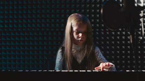 kid plays synthesizer in music record studio. little performer adjusts digital instrument sound in artistic center. girl setups electric piano