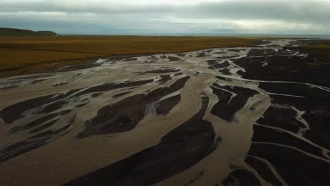 aerial landscape view of a glacier river with many branches flowing in a valley, on dark sand, iceland