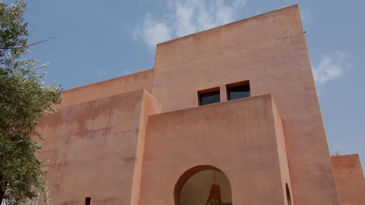 Wide static shot showcasing geometric architecture of building with clear blue sky in the background, Marrakech, Morocco, emphasizing shapes and color contrast