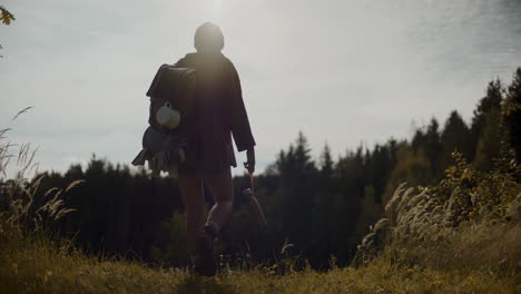 turista femenina con mochila y botella explorando el bosque