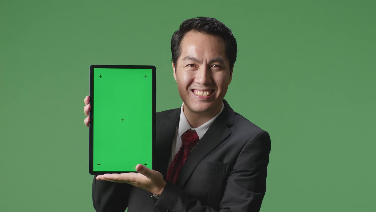 스튜디오에서 녹색 스크린 배경에 태블릿 녹색 화면을 보여주는 아시아 사업가