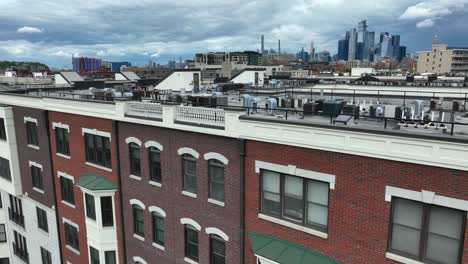 Close-up-descending-shot-of-brick-apartment-building-in-Hoboken-New-Jersey-with-Midtown-Manhattan-skyline-in-distance