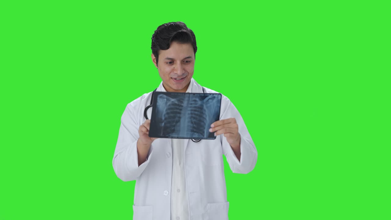 Happy Indian doctor checking X ray report Green screen