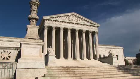 sunlight reflects on the white stone steps and bright white pillars of the us supreme court building entrance