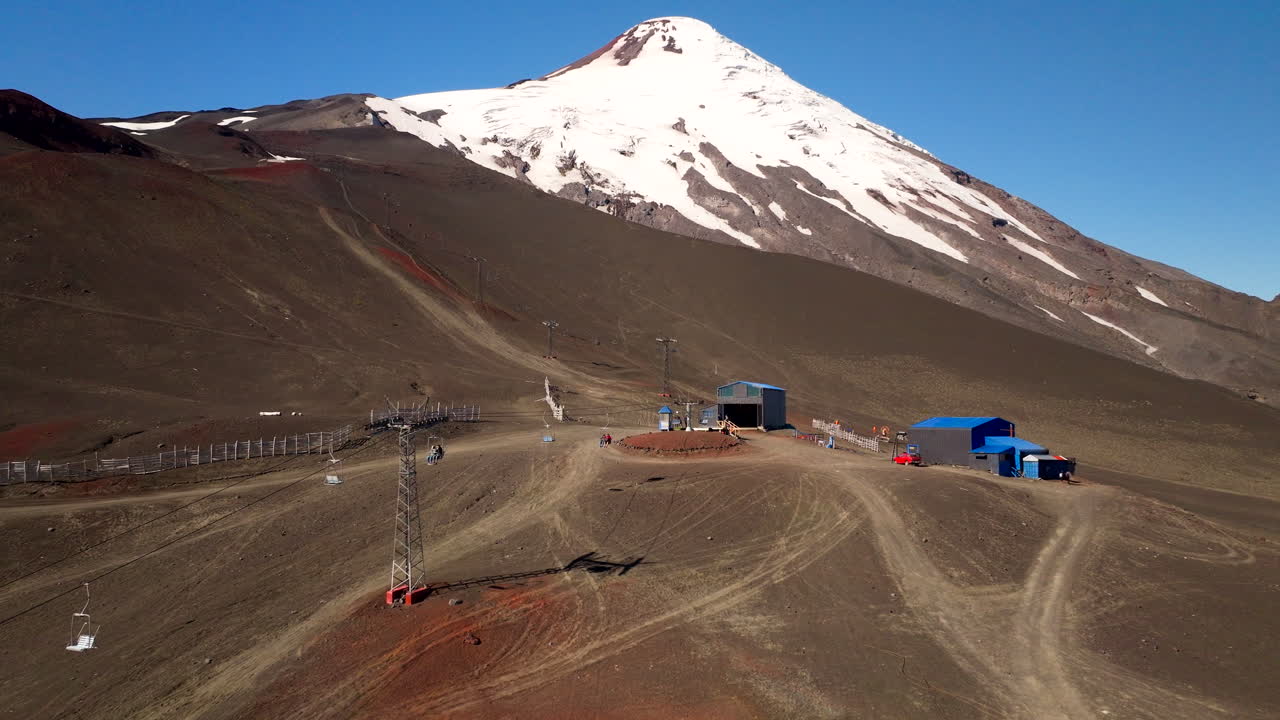 Cable car transports travelers up to Osorno volcano over barren terrain, aerial