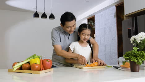 father and daughter cutting carrot.