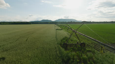 irrigation system extends over a green field in dardanelle, ar during the day, mountains in distance