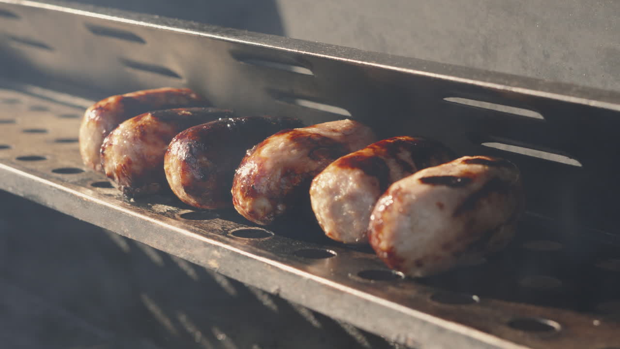Pork Sausages Resting After Cooking on BBQ in Summer Evening Lighting with Smoke Rising from Below