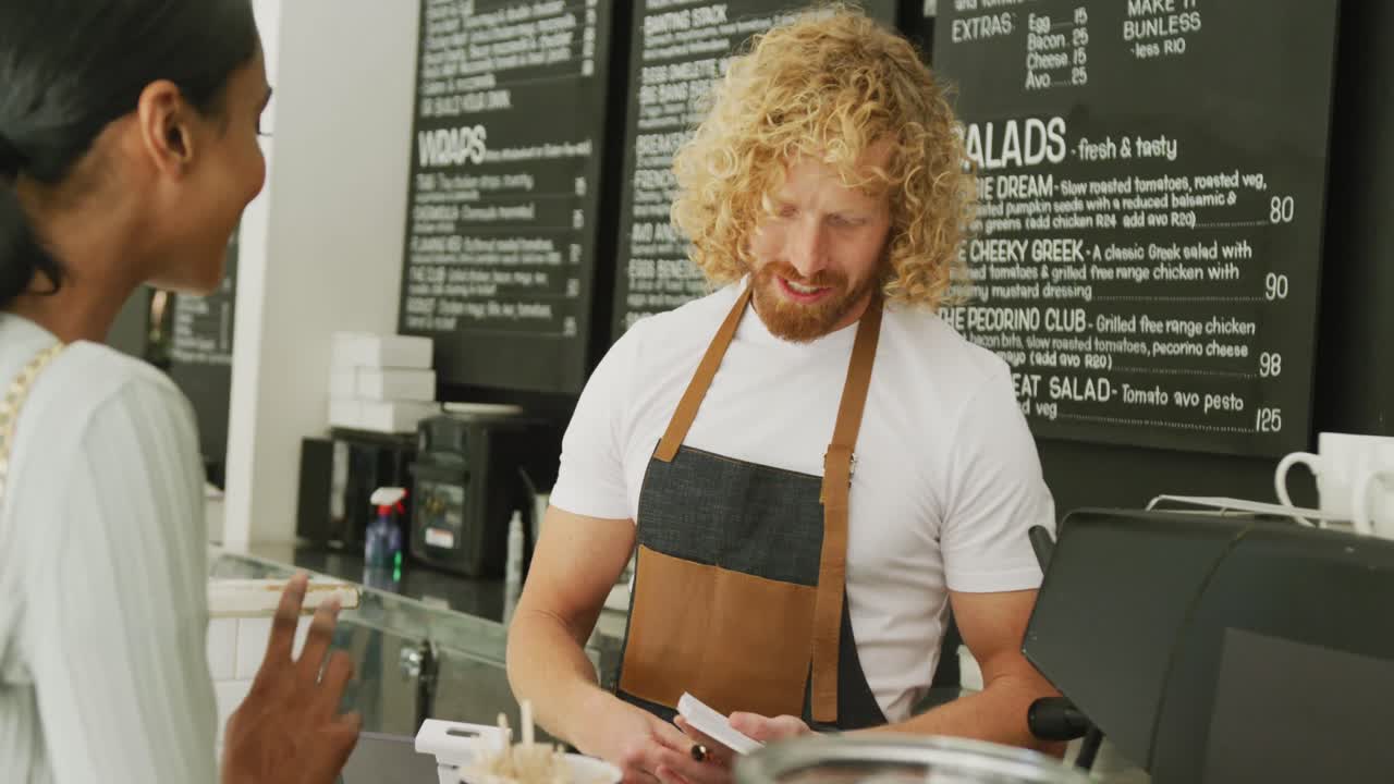 una mujer feliz y diversa ordenando café y hablando con un barista masculino en un café.