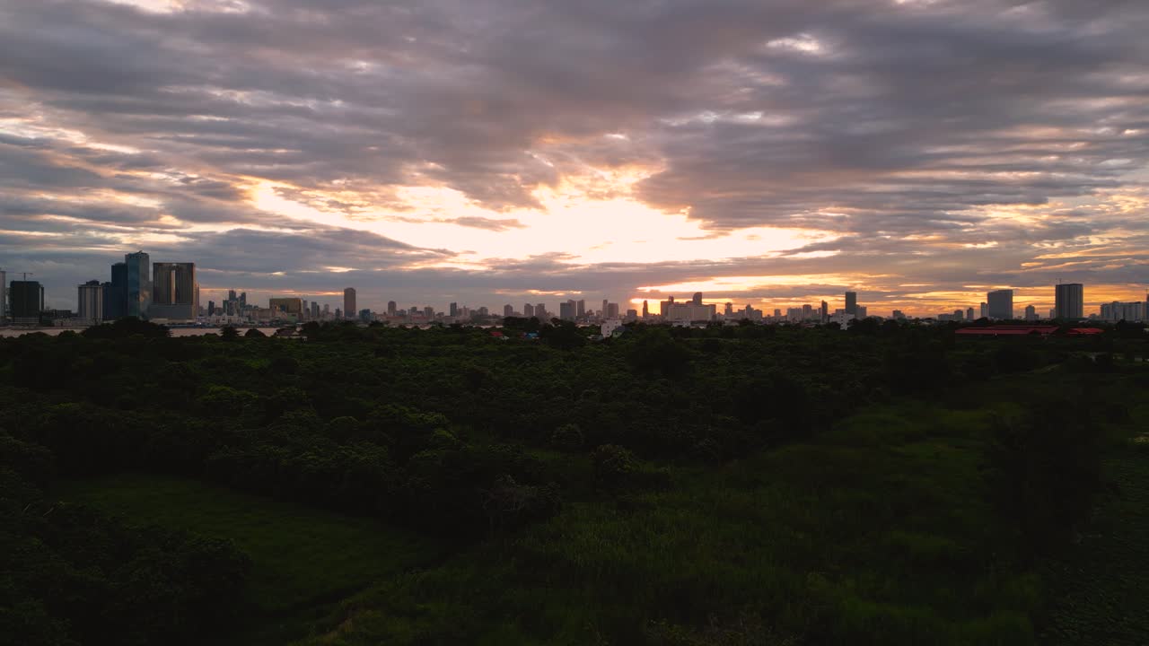 fotografía de un avión no tripulado que revela un gran campo forestal con vistas al paisaje urbano de phnom penh al atardecer