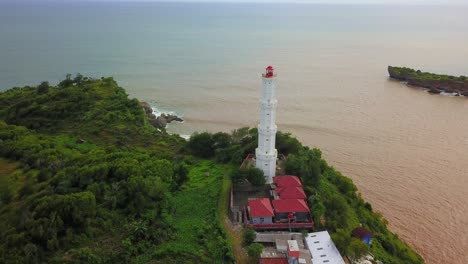 Vista-Aérea-Del-Imponente-Faro-Blanco-Sobre-La-Playa-De-Baron-En-La-Isla-De-Java,-Indonesia