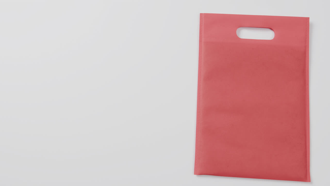 Primo piano di borsa rossa su sfondo bianco, spazio per il testo, rallentatore