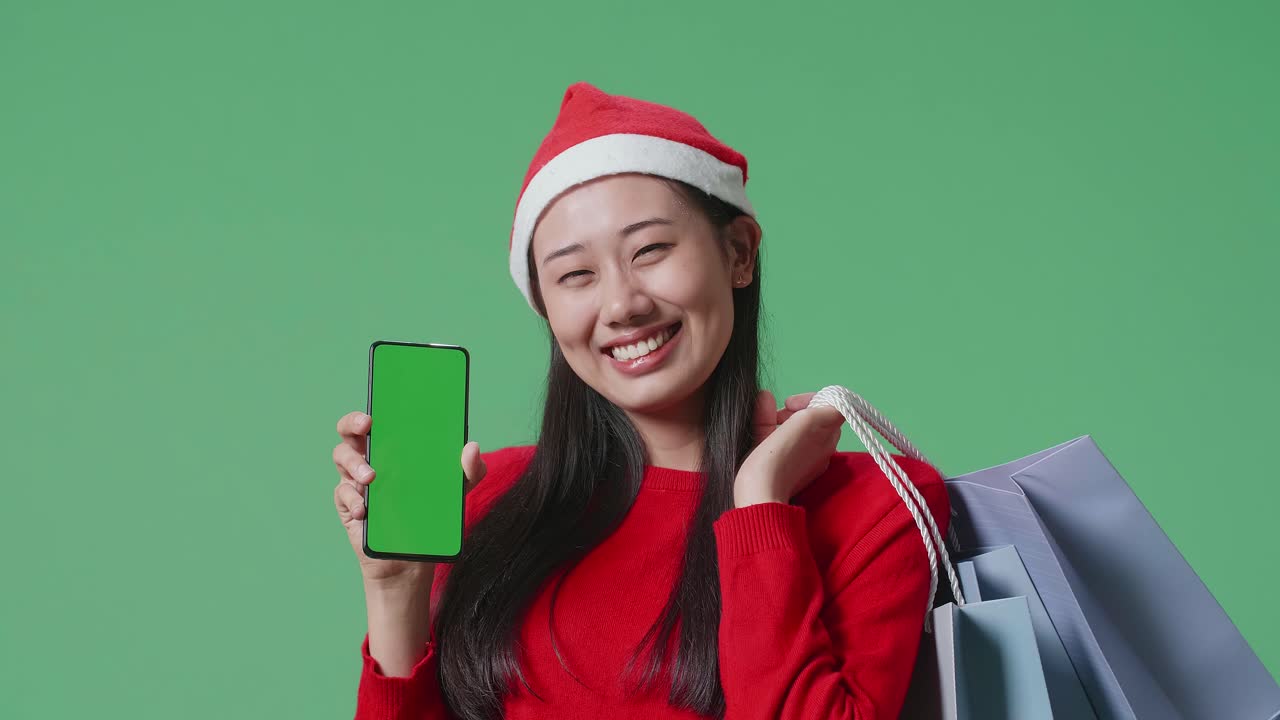 mujer en sombrero de santa con bolsas de compras y un teléfono