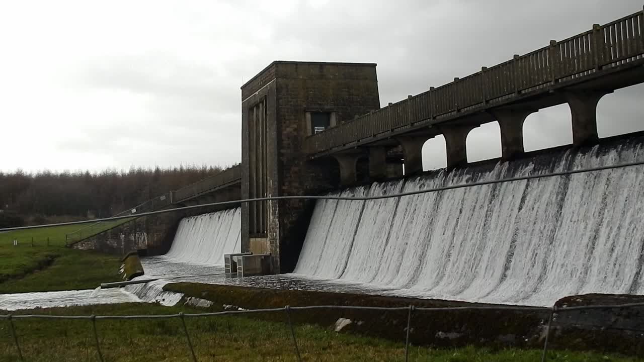 Llyn Cefni reservoir concrete dam gate bridge pouring from Llangefni lagoon, Anglesey rural scene