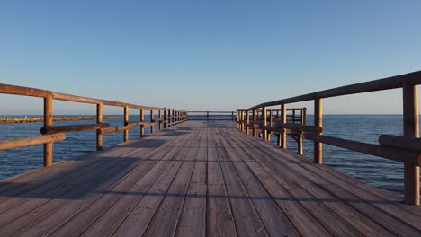 a fishing pier stretching out over the ocean - flying low just over the pier and then over the railing and the open sea