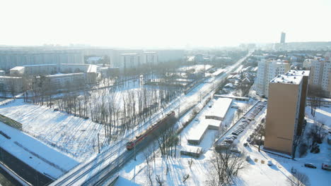 aerial view of local train moving across the bridge in winter gdansk, poland, snow-covered city from the top