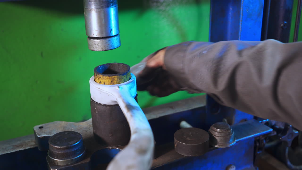 Metal short tubes taken out of pile. Turner's hand holding the detail with a long handle. Close up.