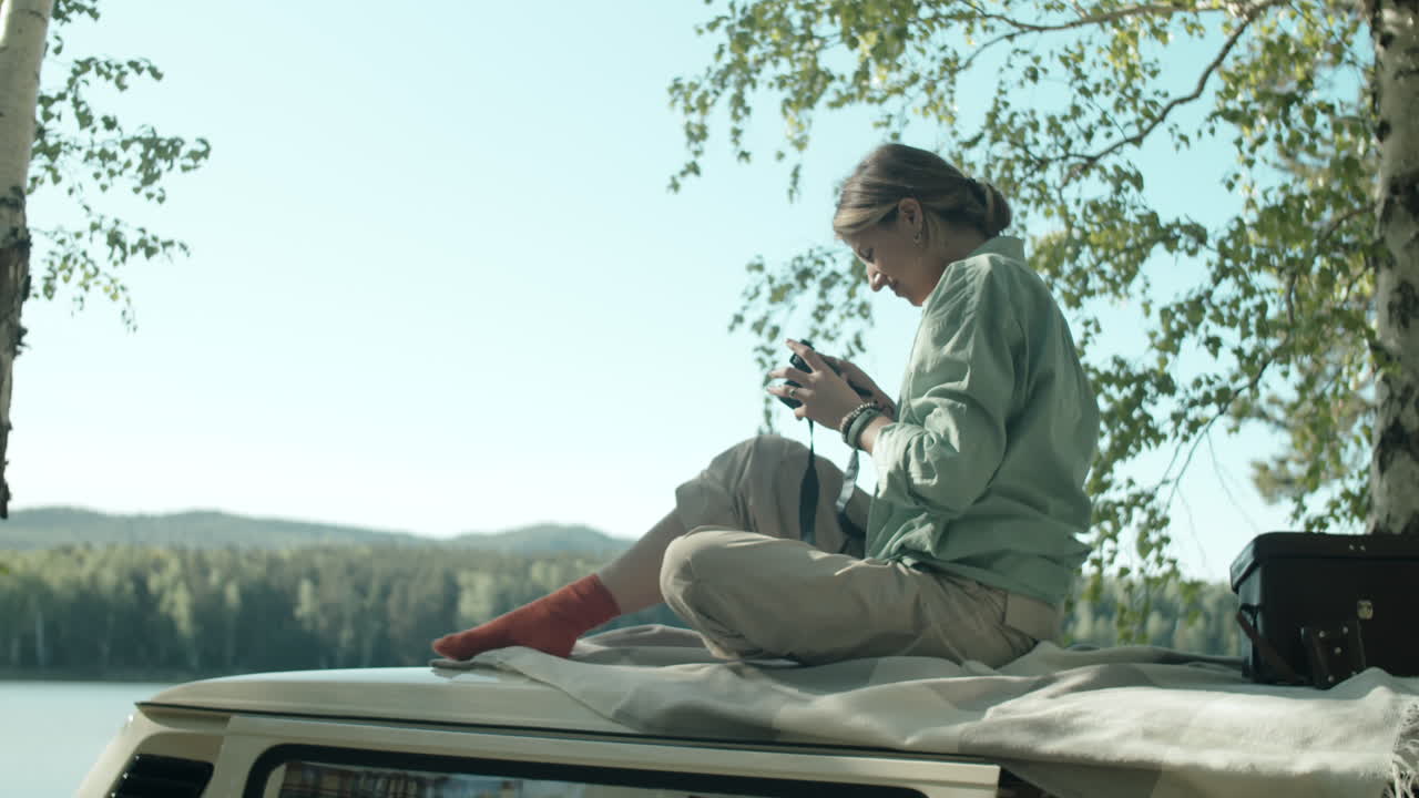 Woman Sitting on Trailer Roof and Photographing Nature