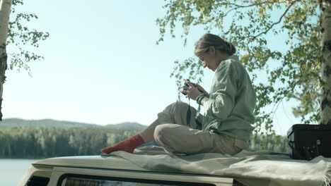 woman sitting on trailer roof and photographing nature