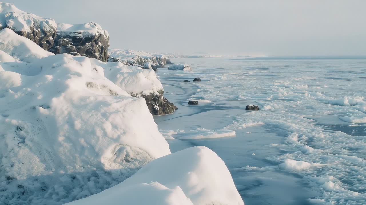Panning camera revealing snowy rocks, ice floes and distant outcrops on frozen sea, copy space