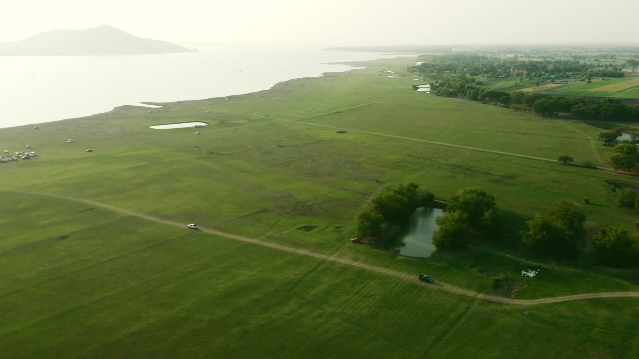 Aerial view shot of Landscape at the end of Pa Sak Jolasid Dam with green grass and water