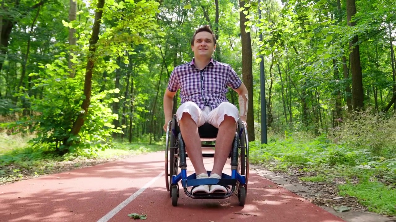 Young Man in Wheelchair Resting on a Red Path in a Green Park