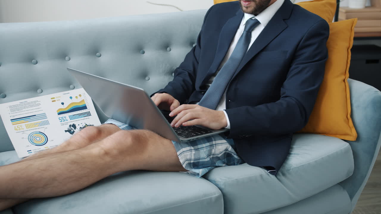 Uomo d'affari che lavora al portatile sul divano