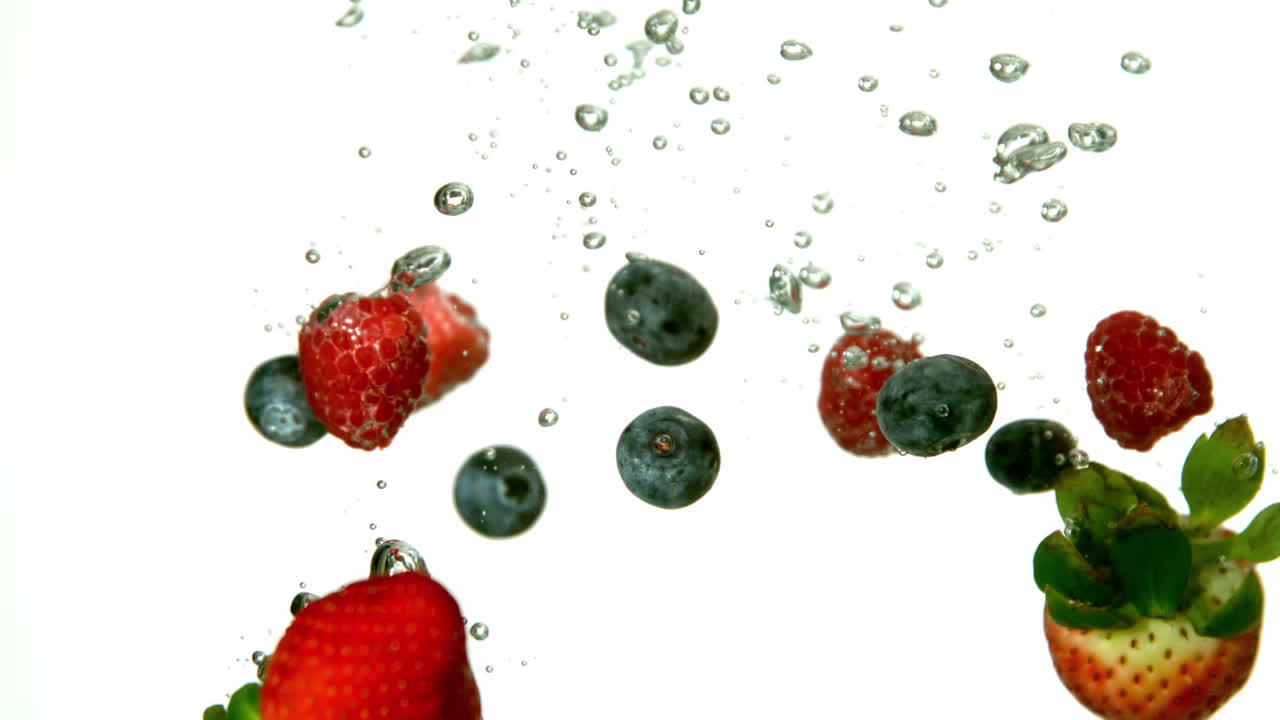 Berries falling in water on white background