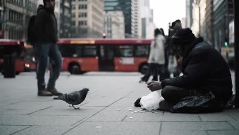 a person sits on the sidewalk in a busy urban area, collecting coins while pedestrians and vehicles pass by. the atmosphere reflects a contrast between hustle and hardship.