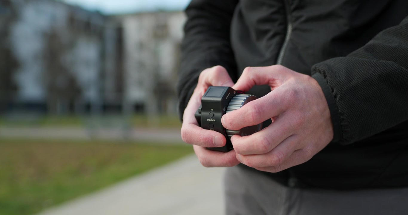 Primer plano de manos caucásicas ajustando su equipo de videografía: módulo de enfoque
