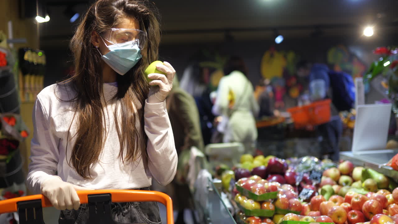 mujer comprando manzanas en una tienda de comestibles durante una pandemia