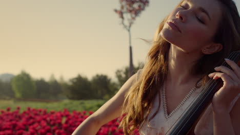 inspired woman with cello making solo concert in beautiful spring park outdoors.