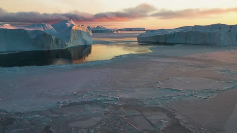 Drone-shot-flying-over-ice-in-middle-of-icebergs,-sundown-in-Illulissat,-Greenland