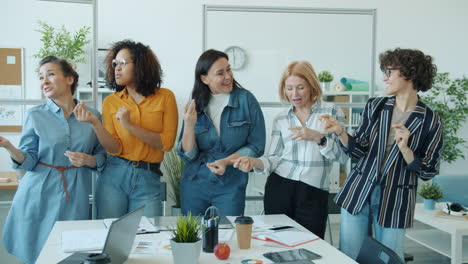 happy women dancing in an office