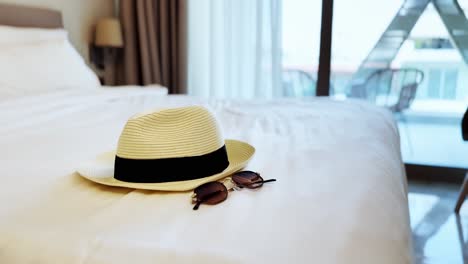 summer vacation essentials with hat and sunglasses on a hotel bed