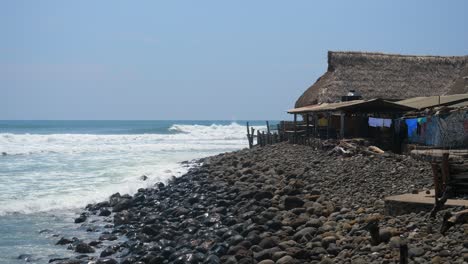 full shot, scenic view of the hut on the rocky beach front in the bitcoin beach in el salvador, mexico, tall waves and bright blue sky in the background