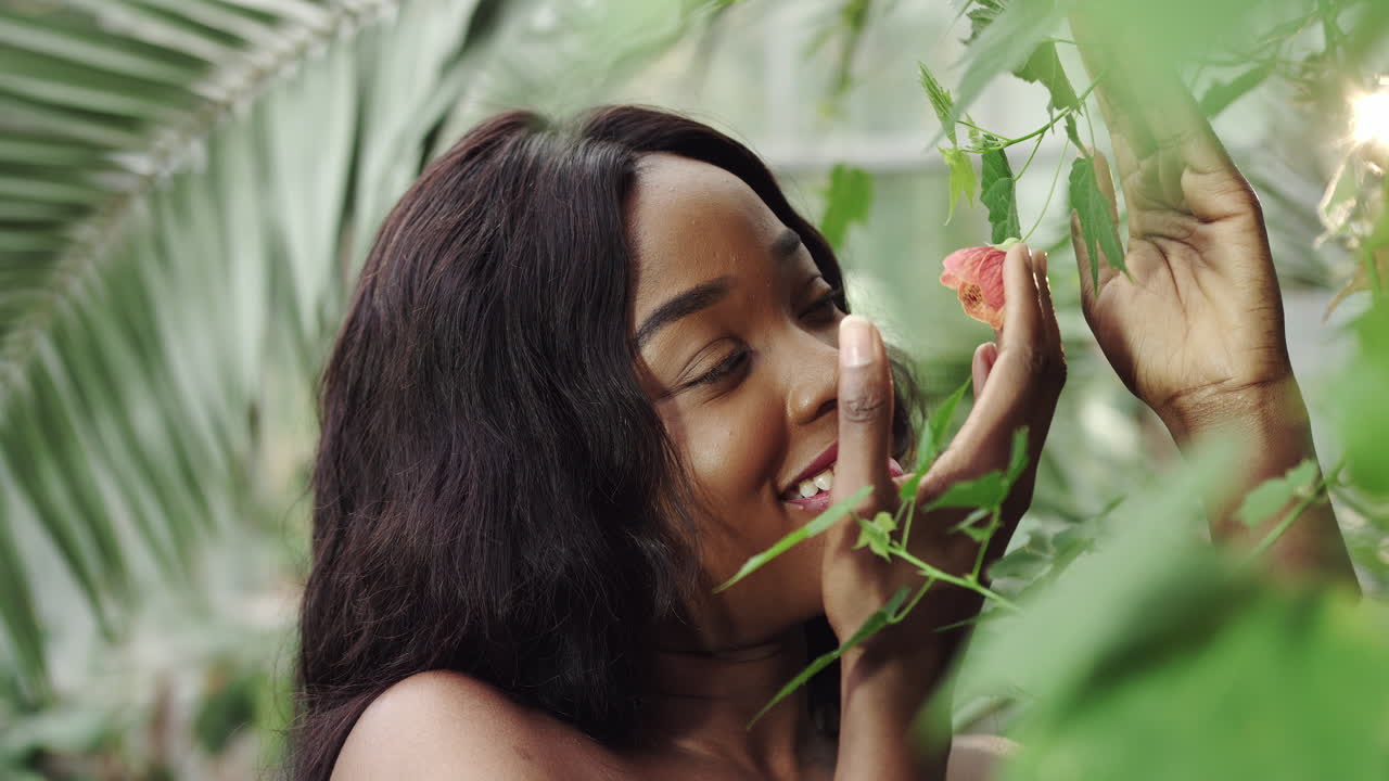 Giovane e bellissima donna afroamericana con trucco naturale nel giardino botanico della foresta pluviale