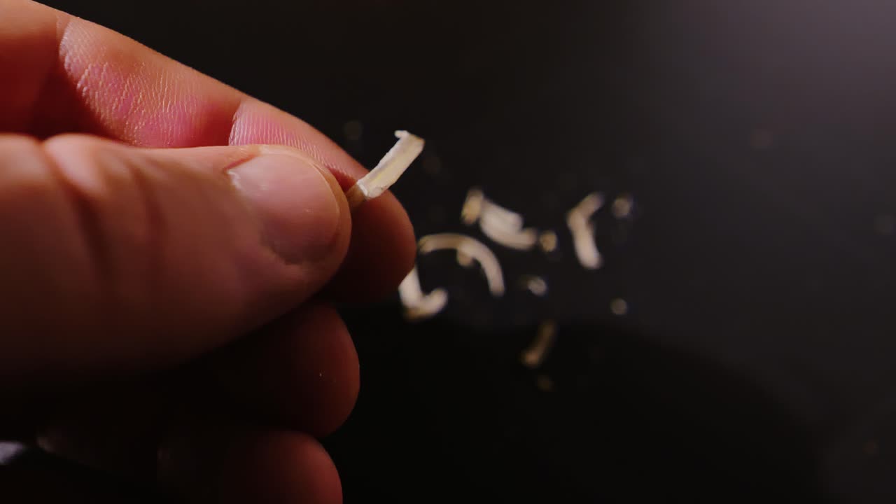 Detailed view of fingernails gripping sharp-edged toenail on black surface