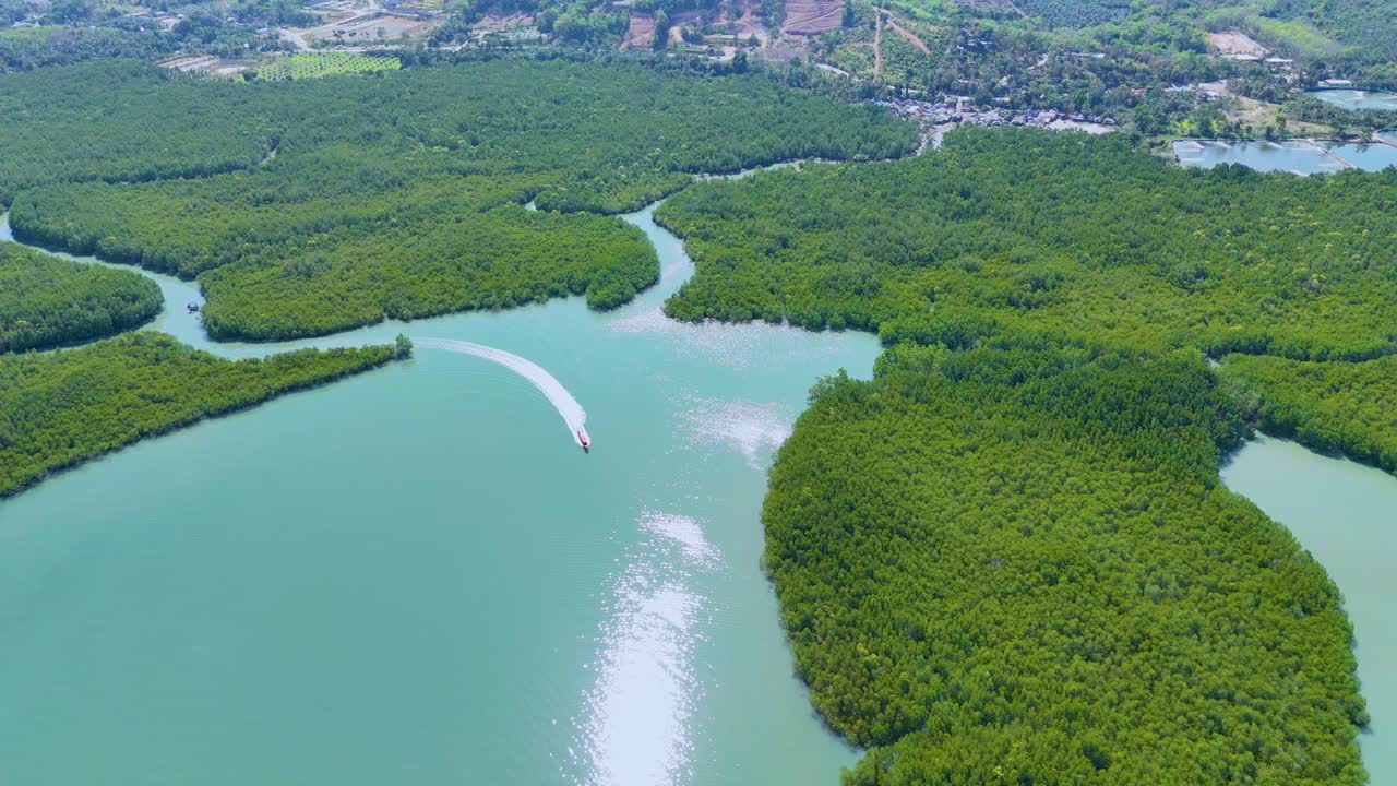 드론 영상은 태국 나가 만의 울창한 맹그로브를 통해 항해하는 배를 포착합니다. 활기찬 초록색과 푸른 물을 보여줍니다.