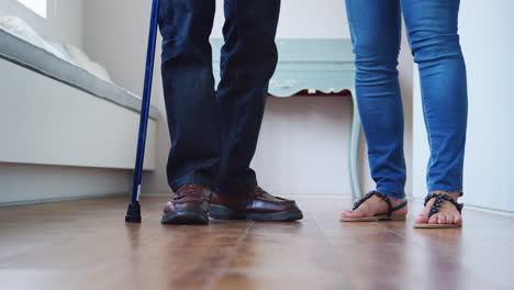enfermera ayudando a un anciano a caminar usando un bastón, sección baja