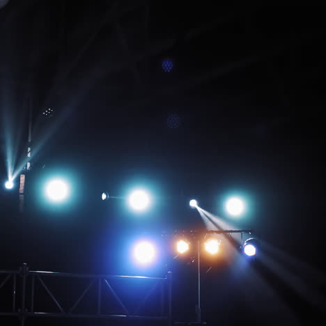 colorful lights from projectors shining brightly inside the club. flashing rays with blue and orange colors from spotlights in dark auditorium.