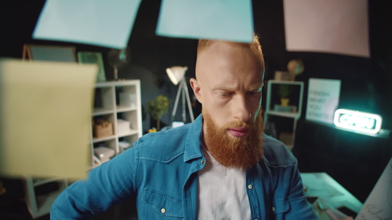 Red head hipster guy putting sticker on ideas board in office. Man reading notes