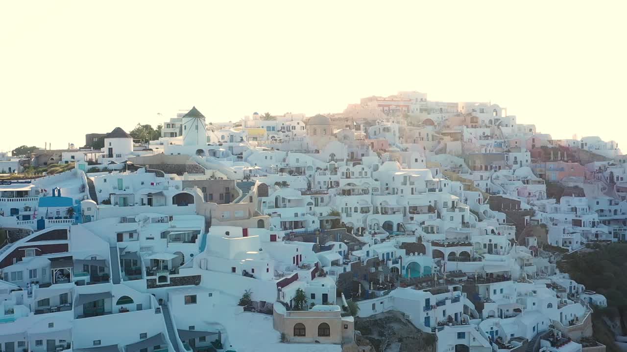 increíble video del famoso pueblo pintoresco blanco y colorido de oia construido sobre un acantilado al atardecer, isla de santorini, cícladas, grecia